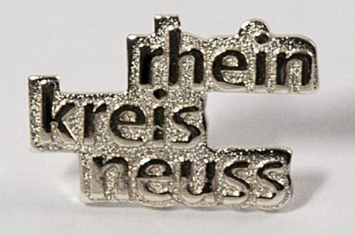 Ein silberfarbener Ansteck-Pin mit dem Schriftzug "rhein kreis neuss" 