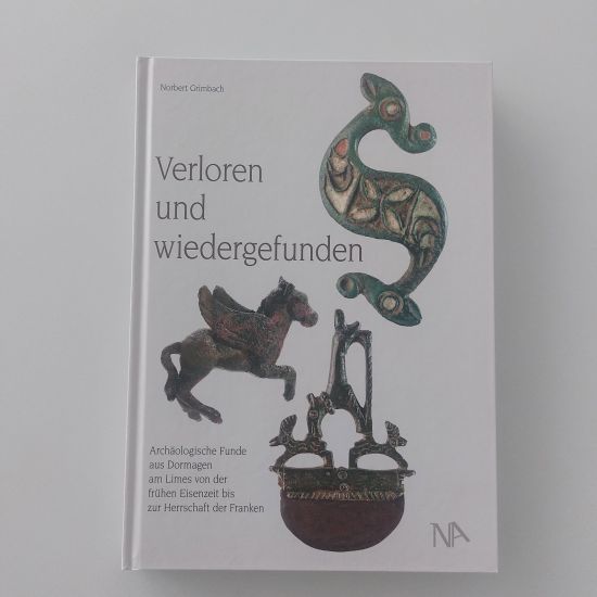 Ein geschlossenes Buch auf einem Tisch, mit einem einfachen Cover-Design. Der Titel "Verloren und wiedergefunden" ist deutlich sichtbar und das Buch scheint in gutem Zustand zu sein, bereit zum Lesen oder zur Aufbewahrung in einer Bibliothek.